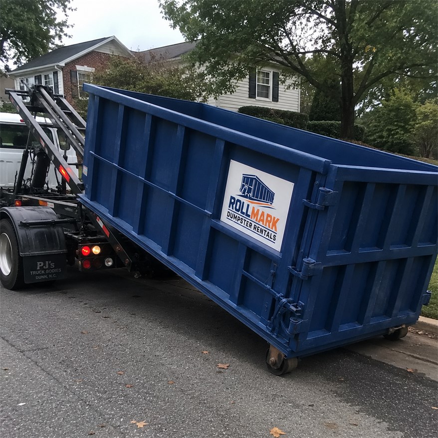 Blue Rollmark roll-off dumpster being delivered